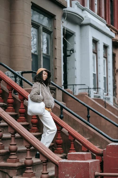 Neighbor parent with a tote bag on a brownstone stoop
