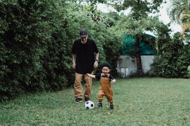 Dad in a cap walking home with a small child after practice