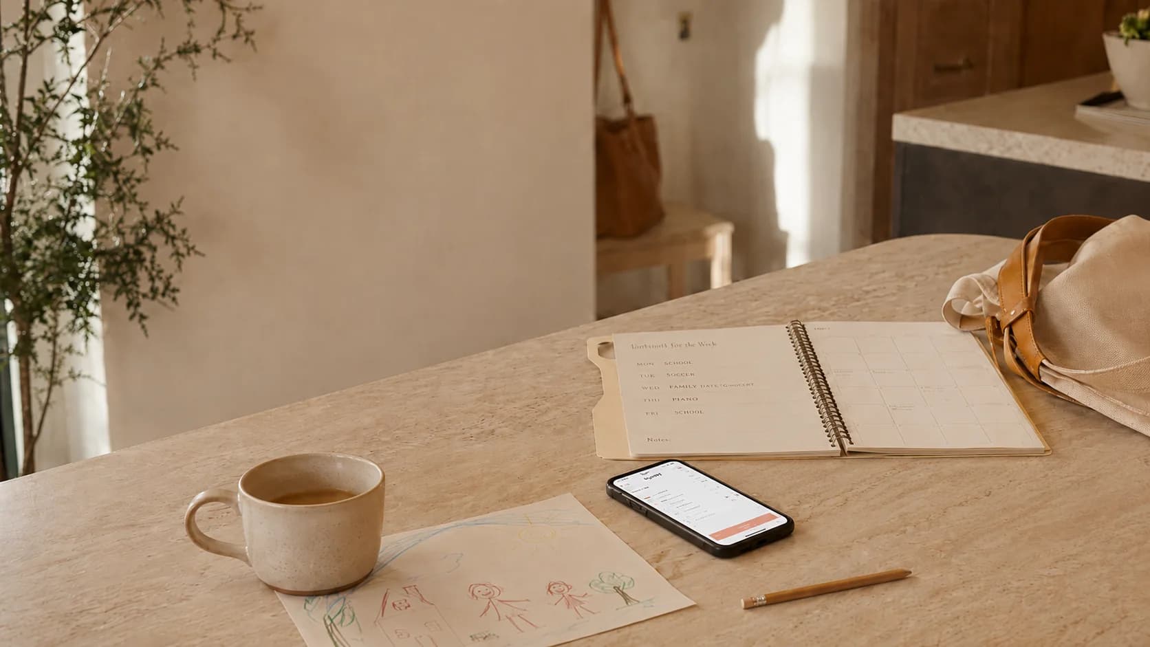 A warm kitchen table with a planning notebook, child's drawing, and phone